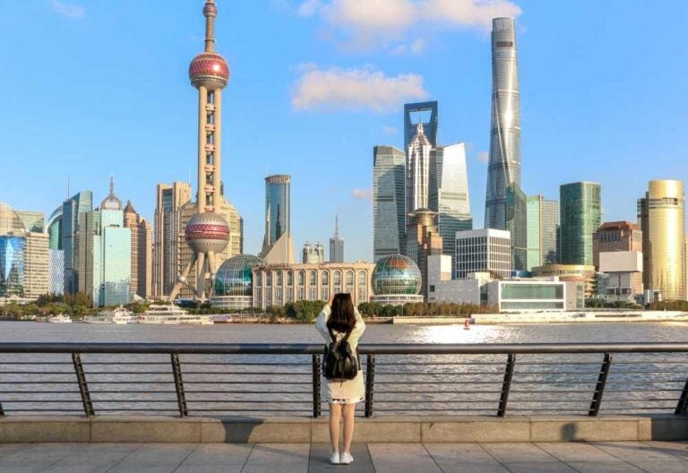 Una turista sul Bund di Shanghai mentre scatta una foto dell'iconico panorama dello skyline di Shanghai a Lujiazui.