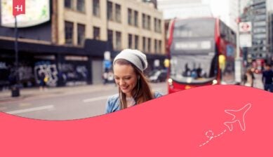 Giovane donna che utilizza uno smartphone sul marciapiede in città