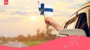 Persona alla guida di un'auto con una bandiera finlandese.