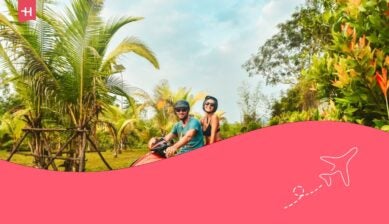 Coppia felice e sorridente che viaggia in motorino in elmetto di sicurezza durante una vacanza tropicale sotto le palme sull'isola di Phu Quoc , Vietnam