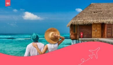Coppia in abito bianco su un molo di una spiaggia tropicale vicino a una villa sull'acqua alle Maldive