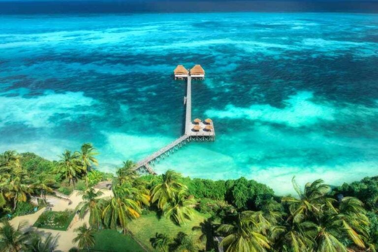 Vista dall'alto ripresa con un drone di un hotel in legno, acque azzurre, piscina e palme verdi. Resort di lusso a Zanzibar.