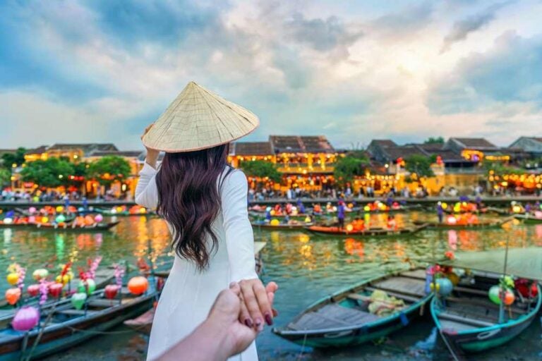 Turista che tiene per mano un uomo e lo accompagna nella città antica di Hoi An, nella città di Hoi An, in Vietnam.