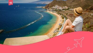 ragazza con cappello seduta ad ammirare il panorama di una spiaggia di tenerife.