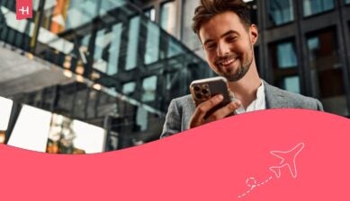 Ritratto di un uomo adulto, attraente, sicuro di sé, moderno, sorridente e felice, vestito con un abito grigio, con un telefono in mano, in piedi all'esterno vicino a un edificio di uffici.