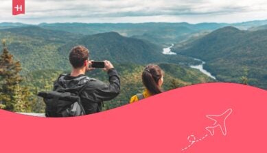 Coppia di escursionisti in campeggio nel Parco Nazionale del Quebec, mentre passeggiano con gli zaini in spalla e scattano una foto del panorama con il cellulare in autunno