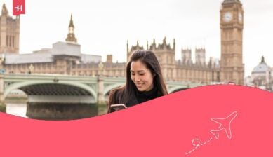 Giovane donna asiatica che guarda il proprio smartphone all'aperto verso la fine dell'inverno nei pressi del Westminster Bridge, a Londra, in Inghilterra.