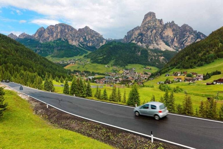 Scena estiva con auto che percorrono un'autostrada attraverso una splendida valle nelle Dolomiti
