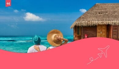 Coppia in abito bianco su un molo di una spiaggia tropicale vicino a una villa sull'acqua alle Maldive