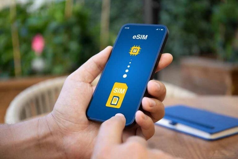 Un uomo tiene in mano un telefono con la schermata che mostra la sostituzione della scheda SIM con l'eSIM.