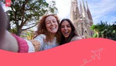 Due amiche felici che si scattano un selfie davanti alla Sagrada Família, mentre si godono la vacanza insieme, guardando la fotocamera e sorridendo.