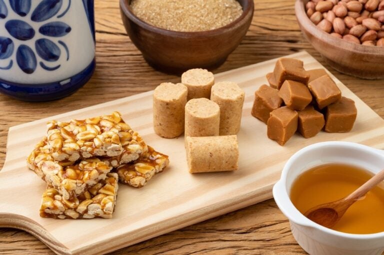 Dolci tradizionali brasiliani con gli ingredienti disposti su un tagliere di legno. Doce de leite o dulce de leche, pé de moleque e pacoca.