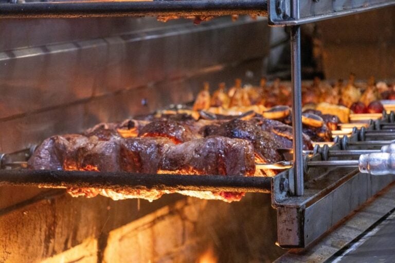 Autentico churrasco brasiliano con picanha e altre carni che arrostiscono sopra una fiamma aperta.
