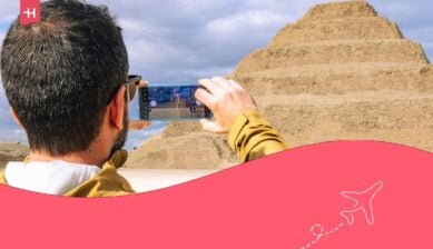 Un turista usa uno smartphone per fotografare l'antica Piramide a gradini di Djoser a Saqqara, Egitto