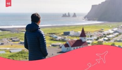 Vista posteriore di un turista in piumino che ammira il panorama della chiesa di Reyniskirkja