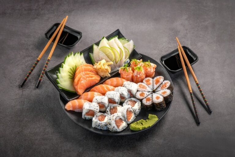 Piatto di sushi con salse su uno sfondo grigio.