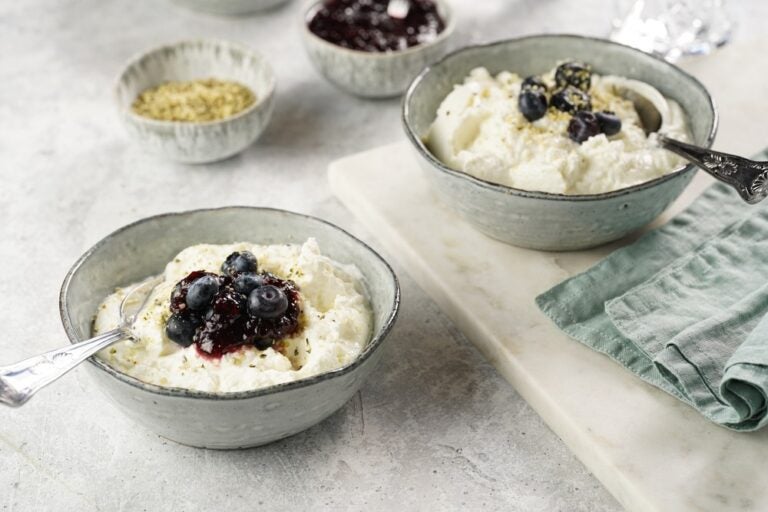 Due ciotole grigie con skyr islandese bianco al naturale, tipico della colazione a base di latticini, accompagnato da marmellata, mirtilli freschi e semi di canapa.
