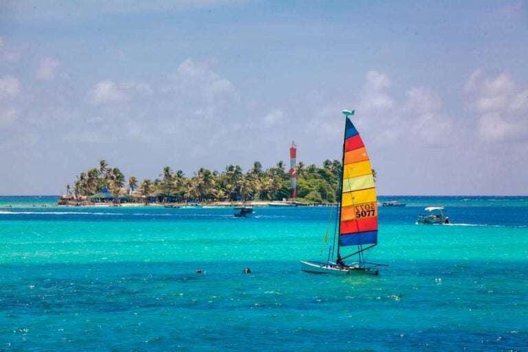 Una piccola barca a vela dai colori vivaci che naviga nelle acque blu e cristalline dell'isola di San Andrés.