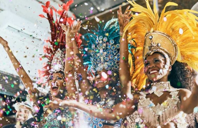 Inquadratura ravvicinata di bellissime ballerine di samba che si esibiscono a un carnevale insieme alla loro banda.