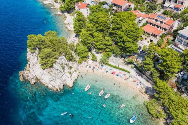 Vista aerea della spiaggia di Punta Rata con barche e mare azzurro a Brela, in Croazia, Dalmazia, Costa Azzurra croata