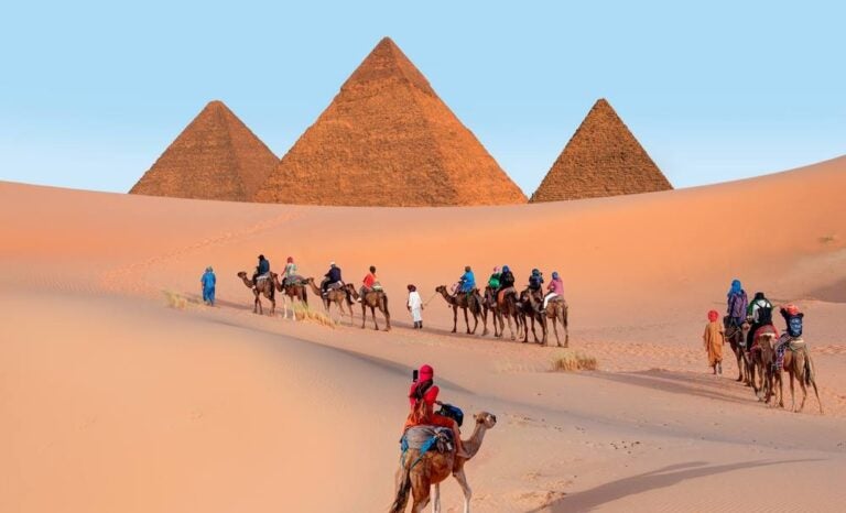 Un gruppo di turisti in sella a cammelli nel complesso delle piramidi di Giza.