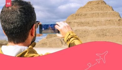 Un turista usa uno smartphone per fotografare l'antica Piramide a gradini di Djoser a Saqqara, Egitto