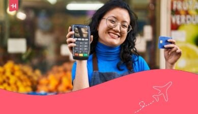 Giovane dipendente cinese con in mano un cellulare e una carta di credito in un negozio di frutta