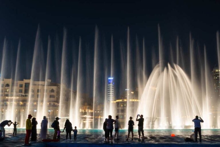 Sagome di persone davanti alla Dubai Fountain di notte, negli Emirati Arabi Uniti