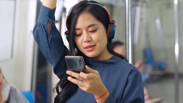 Una donna con il cellulare su un treno pubblico.