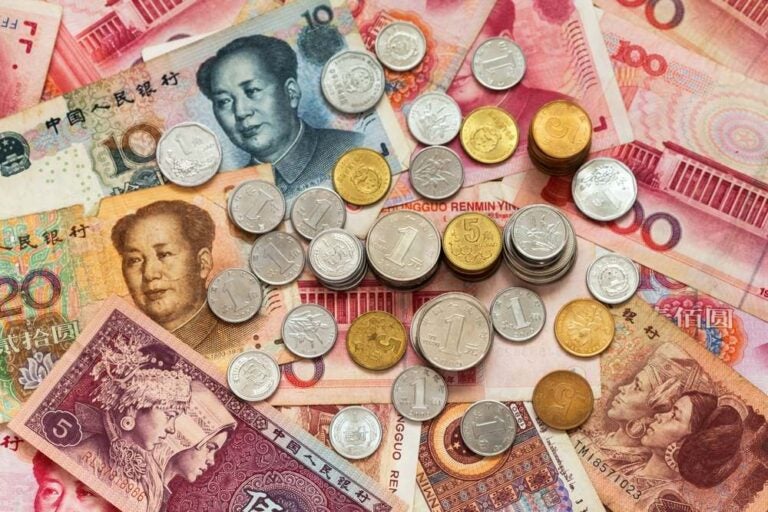 Monete di yuan su una pila di banconote di yuan.