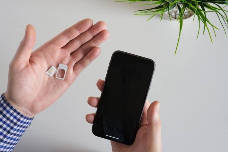 Mano di un uomo che tiene in mano una scheda SIM per uno smartphone.