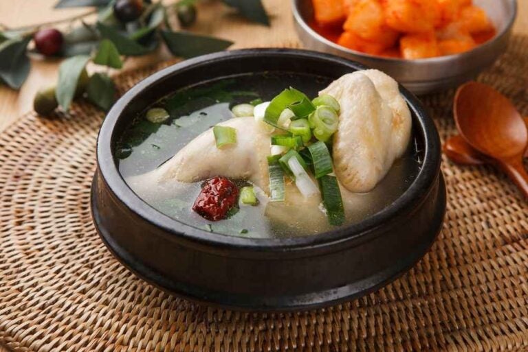 Pentola di pollo intero con brodo trasparente e cipolla verde.