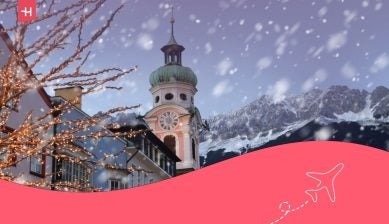 I tetti di Innsbruck con le montagne sullo sfondo e le luci natalizie in primo piano in una serata invernale innevata