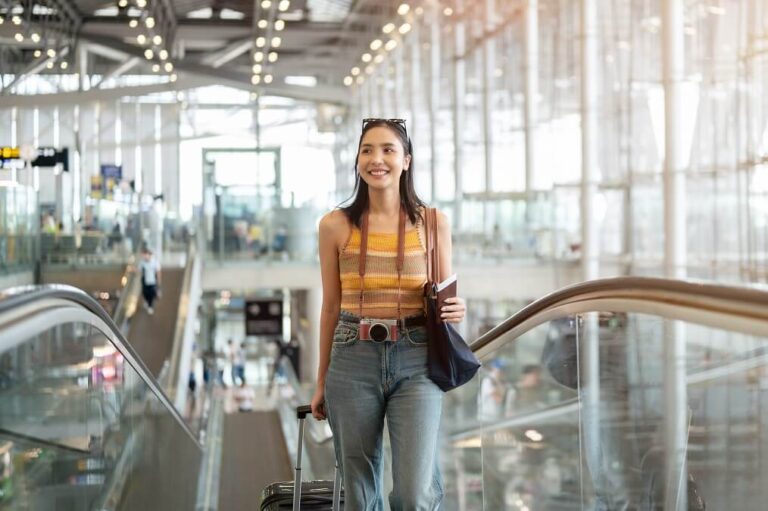 공항 에스컬레이터를 이용하며 웃고 있는 여성