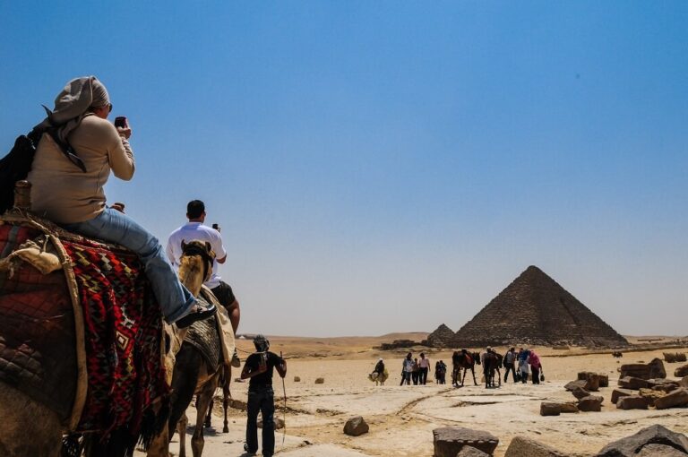 이집트 기자 피라미드 주변에서 낙타를 타고 관광하는 여행자들