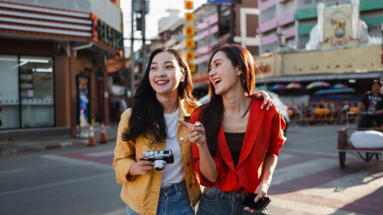 아시아 도시의 활기찬 거리를 함께 걸으며 여행을 즐기는 두 여성 친구