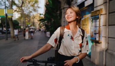 저녁 햇살 아래 자전거를 잡고 미소 짓는 젊은 여성의 클로즈업