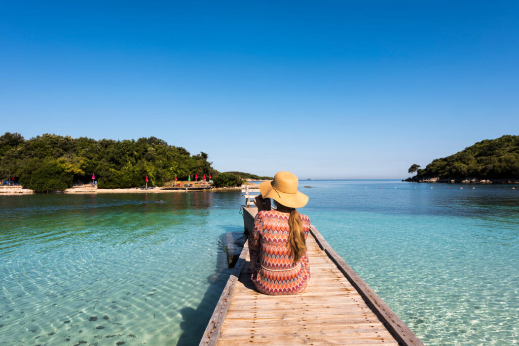 Foto van een vrouw die uitkijkt over helderblauw water in Ksamil, Albanië