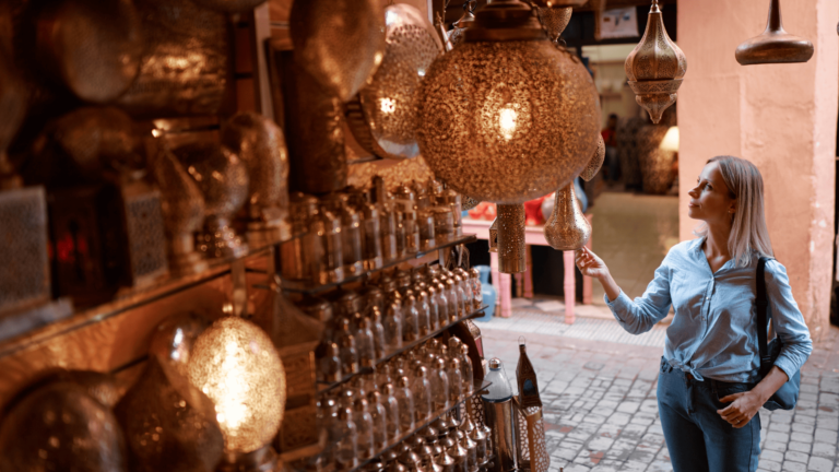 Foto van een vrouw die lampen bewondert bij een kraampje in een souk in Marrakech