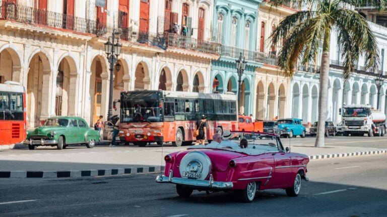 Klassieke roze auto rijdt door de kleurrijke straten van Havana
