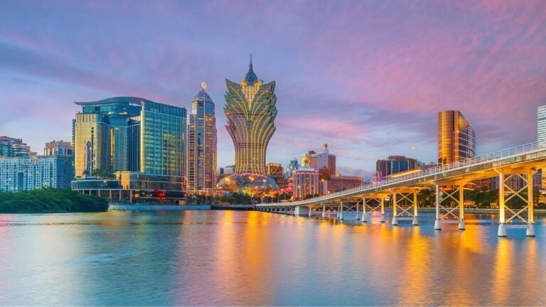 De skyline van Macau tijdens de zonsondergang met het iconische goudkleurige Grand Lisboa hotel en de Sai Van brug.