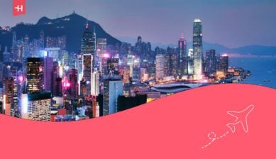 Panoramisch uitzicht op de verlichte skyline van Hong Kong Island en Victoria Harbour tijdens de blauwe avondschemering met wolkenkrabbers.