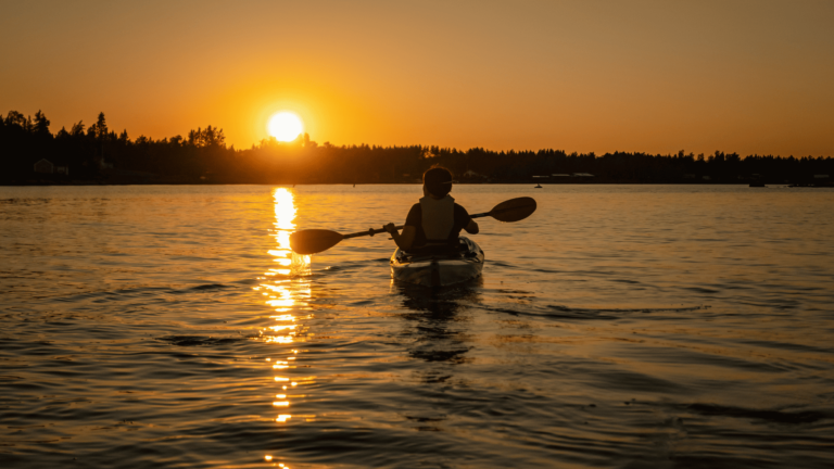 Meisje kajakt onder de middernachtzon in Zweden