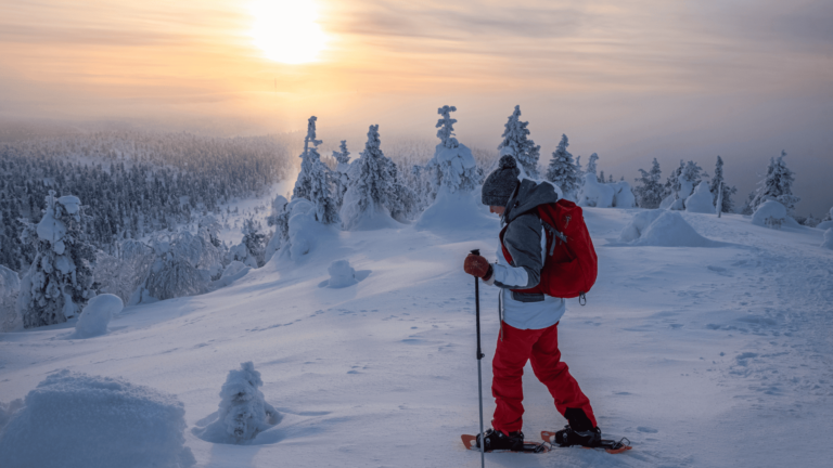 Een vrouw maakt een sneeuwschoenwandeling bij zonsondergang in Lapland