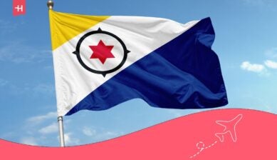 Vlag van Bonaire wapperend in de wind tegen een blauwe lucht, als uitgelichte afbeelding voor een artikel over de beste eSIM voor Bonaire.