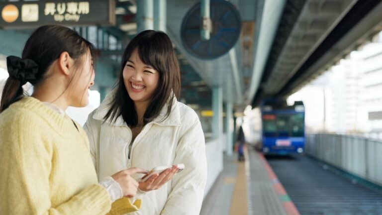 Reizigers die hun smartphone gebruiken op een metrostation in Tokyo tijdens het wachten op het openbaar vervoer.