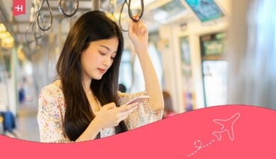 Een reizigster in de trein gebruikt haar smartphone om online te blijven met de beste simkaart voor Maleisië.