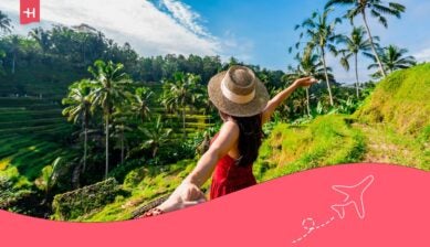 Een persoon houdt de hand vast van een vrouw in een rode jurk en hoed, kijkend over de groene rijstvelden op Bali, Indonesië.