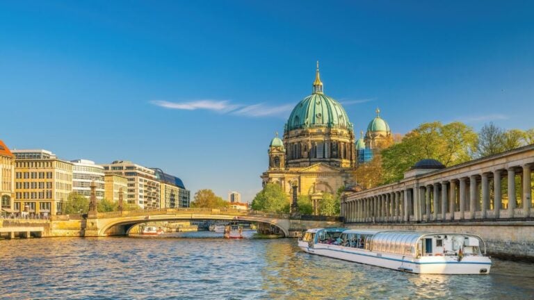 Een zonnig gezicht op de Berliner Dom en de rivier de Spree met een rondvaartboot in Berlijn, een onmisbare culturele stop tijdens de beste stedentrips Europa.
