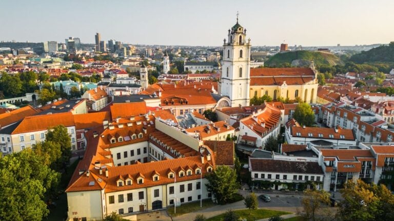 Een prachtig bovenaanzicht van de oude binnenstad van Vilnius met zijn kenmerkende rode daken en de Sint-Janskerk, een van de verrassende beste stedentrips Europa.